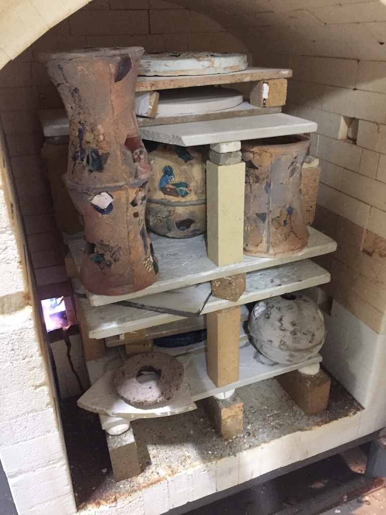 Kiln packed with ceramic sculptures and bowls on shelves, ready for firing